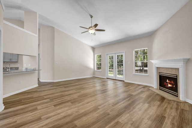 unfurnished living room with sink, a fireplace, hardwood / wood-style floors, and french doors