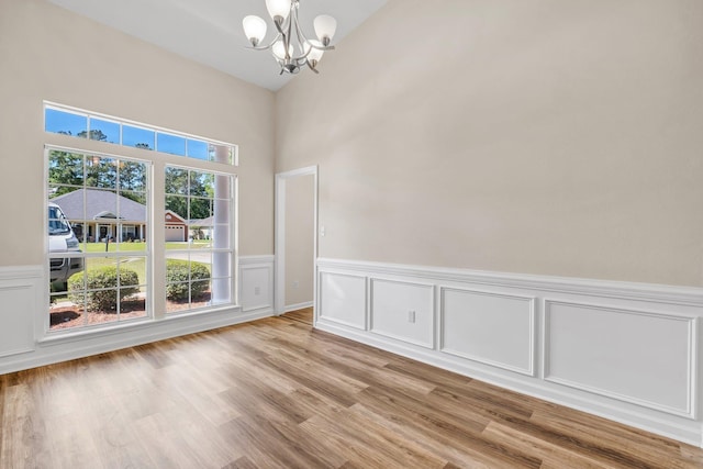 spare room featuring light wood-type flooring and a chandelier