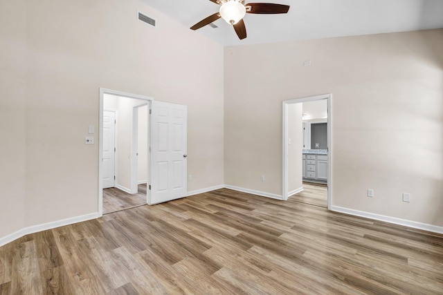 empty room featuring light hardwood / wood-style flooring, high vaulted ceiling, and ceiling fan