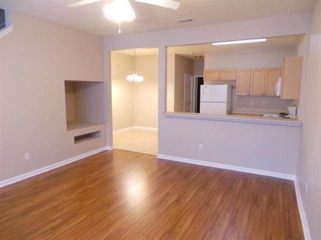 unfurnished living room featuring wood-type flooring and ceiling fan with notable chandelier