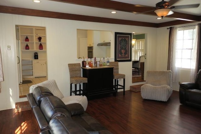 living room featuring ceiling fan, dark wood-type flooring, and beam ceiling