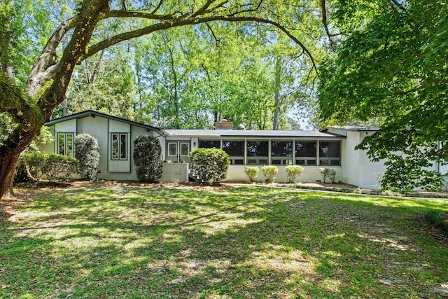 2521 Harriman Cir, Tallahassee, FL 32308 - view of front of property featuring a chimney, a sunroom, a front lawn, and stucco siding