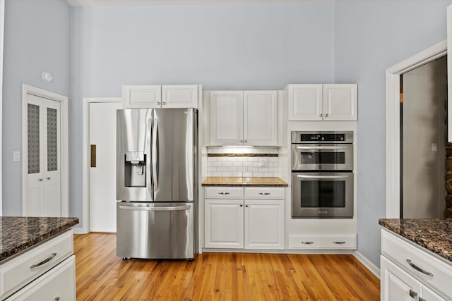 2521 Harriman Cir, Tallahassee, FL 32308 - kitchen with stainless steel appliances, light wood-style flooring, tasteful backsplash, dark stone counters, and white cabinetry