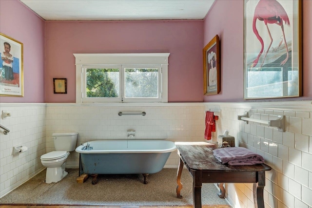 bathroom featuring a tub to relax in, toilet, and tile walls