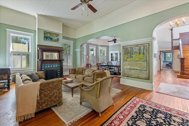 living room featuring hardwood / wood-style floors, a tile fireplace, and ceiling fan with notable chandelier