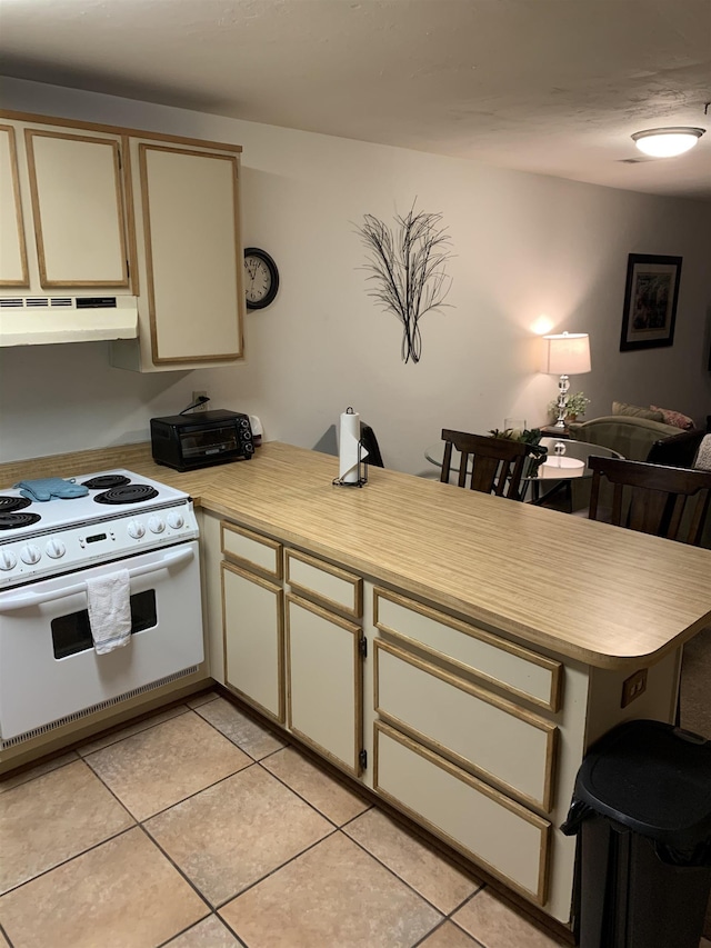 kitchen featuring ventilation hood, kitchen peninsula, cream cabinetry, light tile patterned floors, and white stove