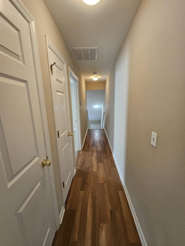 hallway featuring dark hardwood / wood-style flooring and a textured ceiling