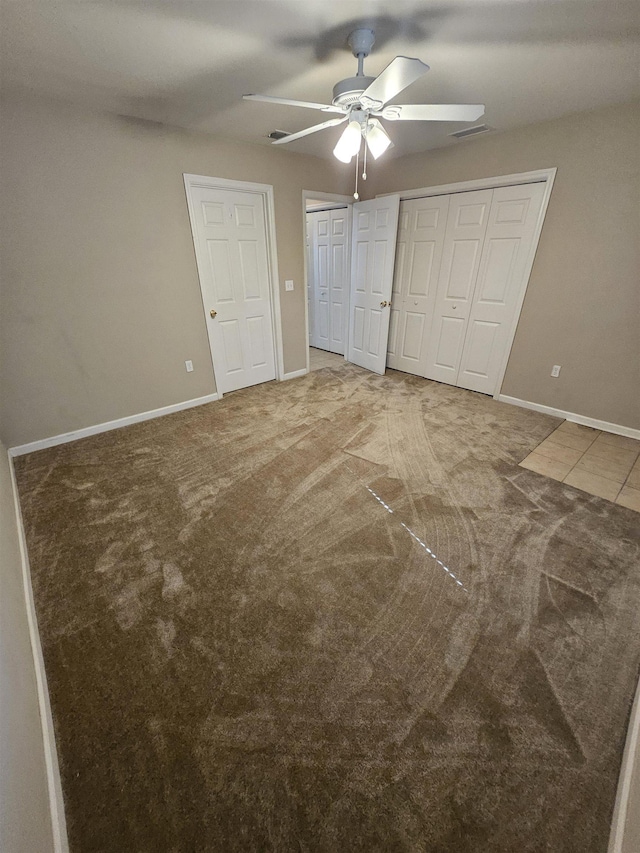 unfurnished bedroom featuring multiple closets, ceiling fan, and carpet floors