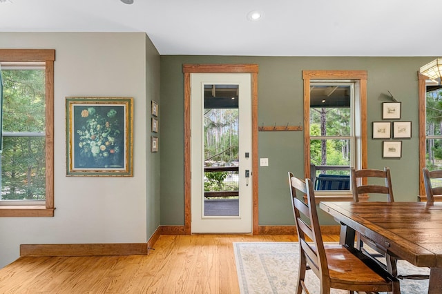 doorway featuring light wood-type flooring, plenty of natural light, and baseboards