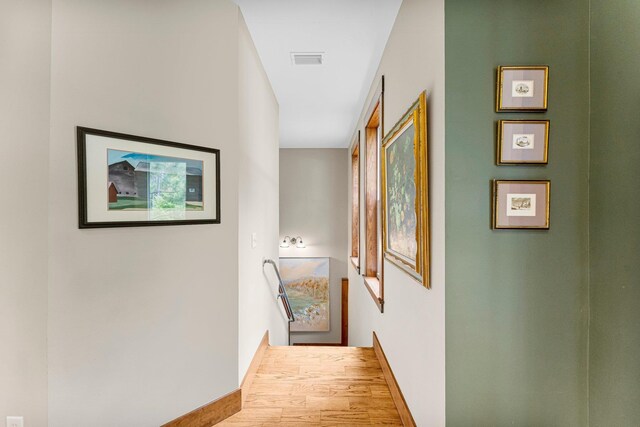 hallway featuring wood finished floors, visible vents, and baseboards