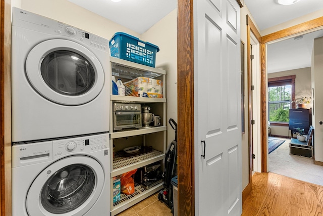 washroom featuring laundry area, stacked washer / dryer, and wood finished floors