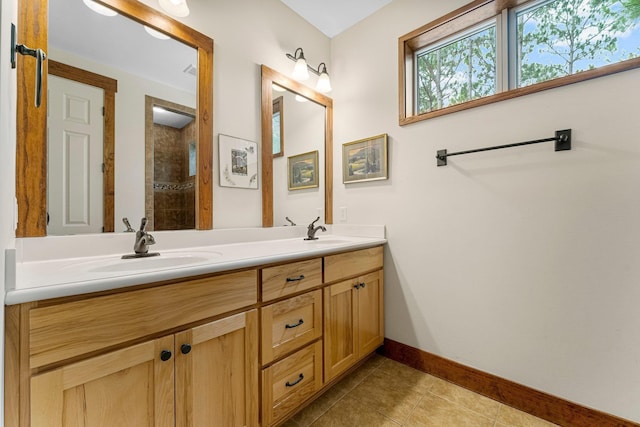 bathroom featuring baseboards, double vanity, a sink, and tile patterned floors