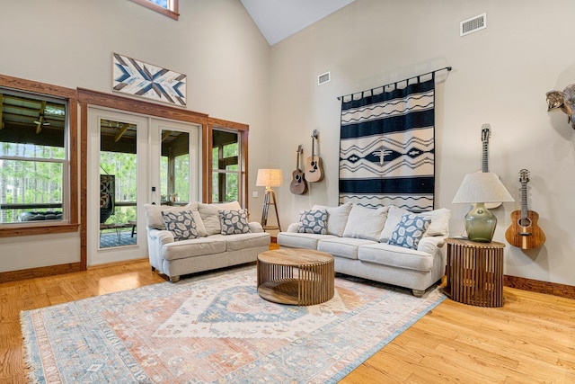 living area featuring high vaulted ceiling, baseboards, visible vents, and wood finished floors