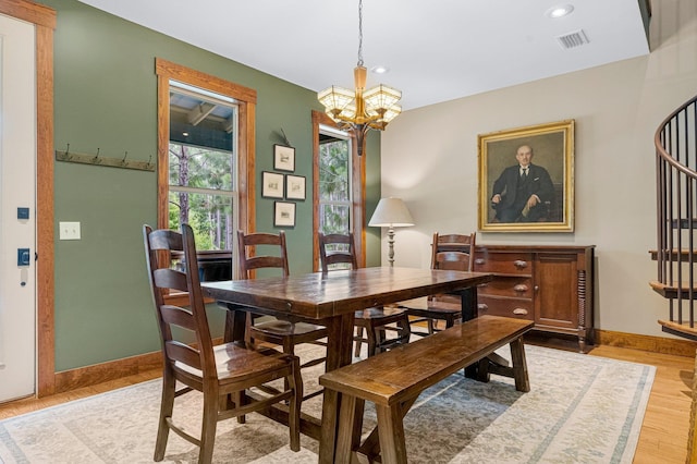 dining room featuring a notable chandelier, visible vents, baseboards, stairs, and light wood finished floors