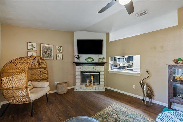 living room featuring a brick fireplace, hardwood / wood-style floors, ceiling fan, and vaulted ceiling