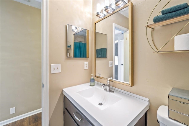 bathroom with wood-type flooring, toilet, and vanity