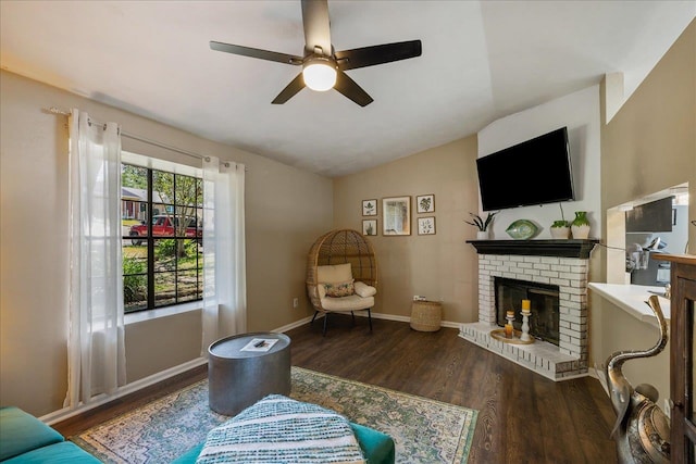 living area with dark wood-type flooring, vaulted ceiling, ceiling fan, and a fireplace