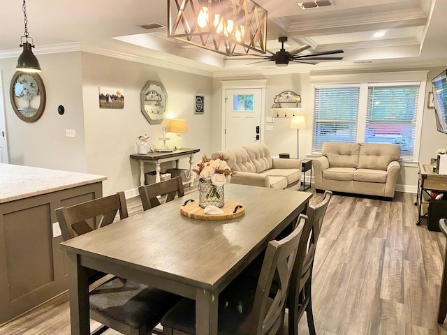 dining room featuring ceiling fan, light hardwood / wood-style floors, a tray ceiling, coffered ceiling, and ornamental molding