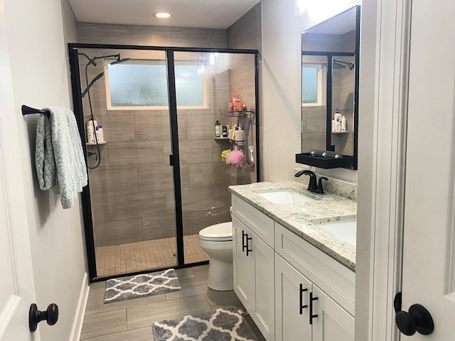 bathroom featuring a shower with shower door, vanity, and toilet