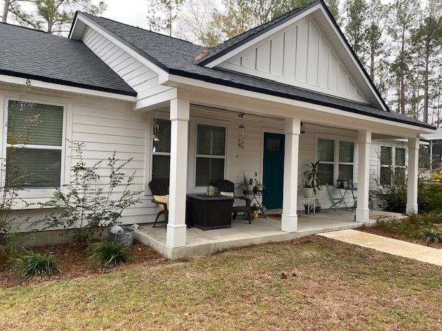 rear view of property featuring a yard and a porch