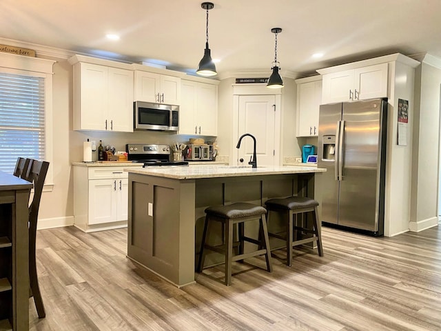 kitchen with light hardwood / wood-style floors, a center island with sink, sink, white cabinetry, and appliances with stainless steel finishes