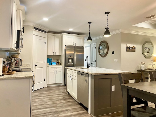 kitchen with a center island with sink, stainless steel appliances, pendant lighting, white cabinets, and light stone counters