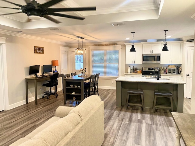 interior space with stainless steel appliances, white cabinets, hanging light fixtures, and a kitchen island with sink