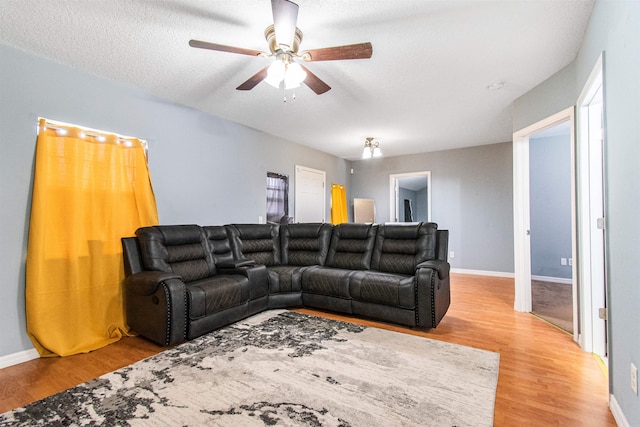 living room featuring ceiling fan, wood-type flooring, and a textured ceiling