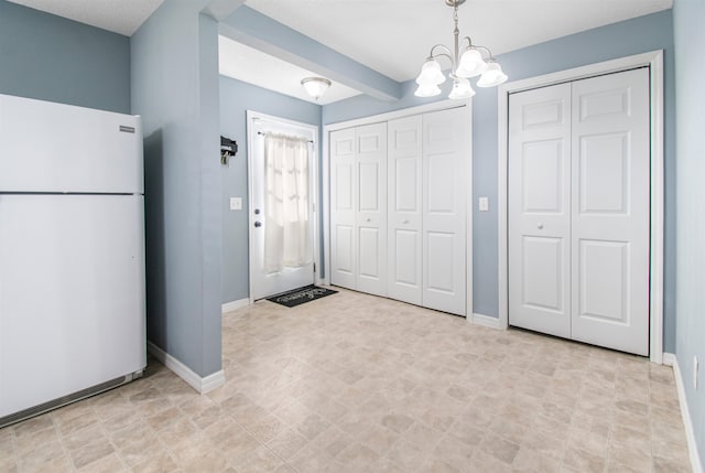 interior space featuring beamed ceiling, white fridge, pendant lighting, and a chandelier