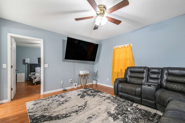 living room featuring a textured ceiling, wood-type flooring, and ceiling fan