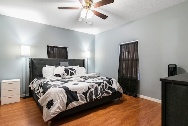 bedroom with ceiling fan, a textured ceiling, and light hardwood / wood-style floors