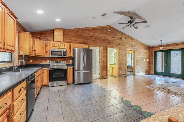 kitchen with french doors, sink, wood walls, vaulted ceiling, and appliances with stainless steel finishes