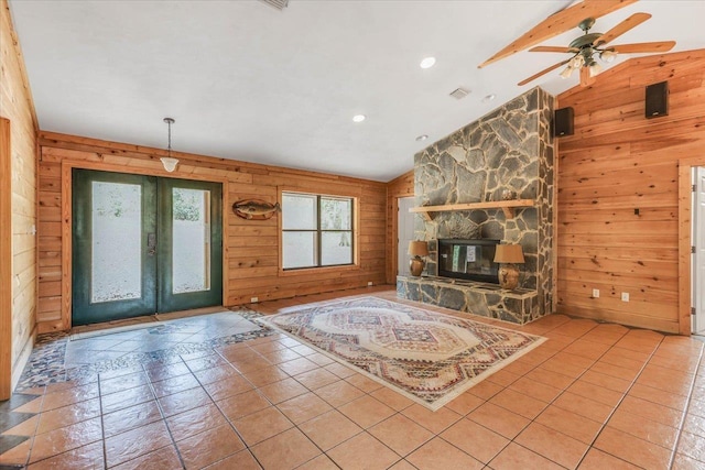 unfurnished living room with french doors, vaulted ceiling with beams, a fireplace, and wood walls