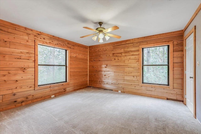 unfurnished room with ceiling fan, light colored carpet, and wooden walls