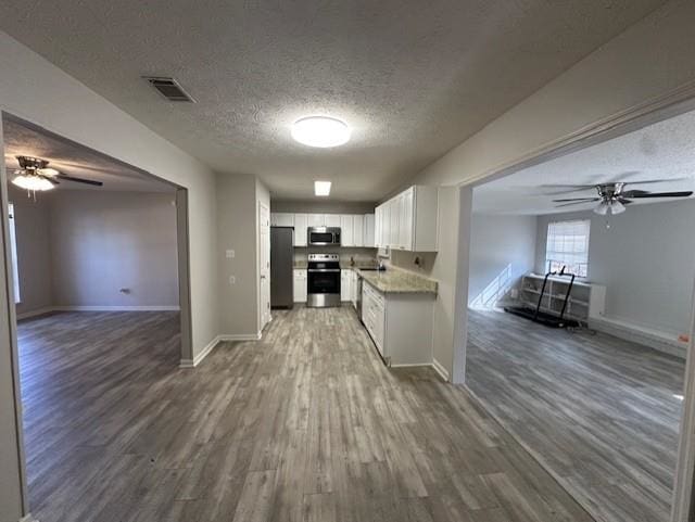 kitchen with appliances with stainless steel finishes, dark hardwood / wood-style floors, white cabinetry, ceiling fan, and a textured ceiling