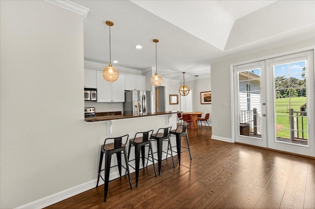 3256 Whitman Way, Tallahassee, FL 32311 - kitchen featuring stainless steel appliances, dark countertops, ornamental molding, a breakfast bar area, and dark wood finished floors