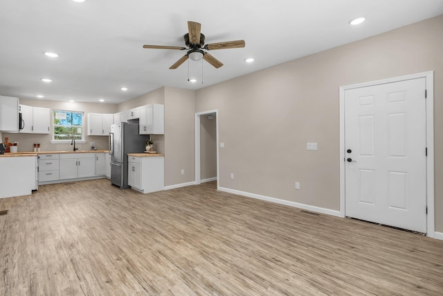 1618 Mayhew St, Tallahassee, FL 32304 - kitchen featuring white cabinets, a ceiling fan, a sink, freestanding refrigerator, and light wood-style floors
