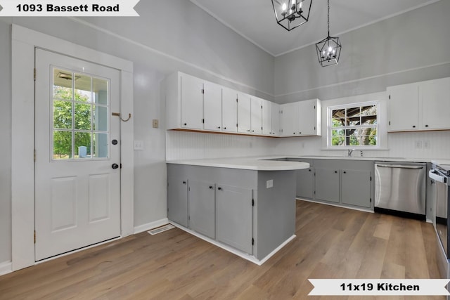 kitchen featuring a peninsula, light wood-type flooring, ornamental molding, a chandelier, and dishwasher