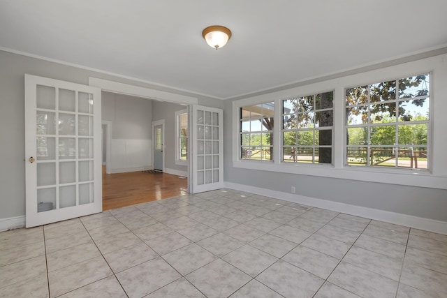 tiled spare room featuring a wealth of natural light, french doors, and ornamental molding