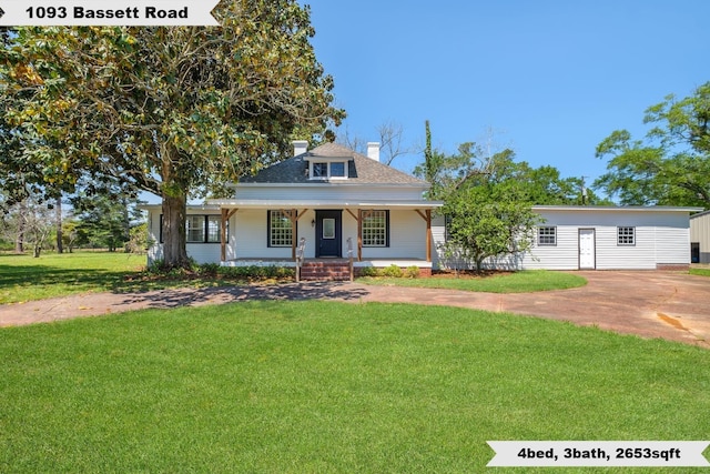 view of front of house with a front yard, a porch, a chimney, and a shingled roof