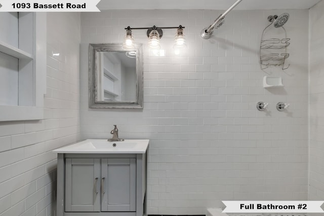bathroom featuring tile walls, tiled shower, and vanity