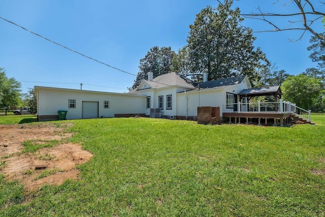 back of property with a yard, a wooden deck, and a garage