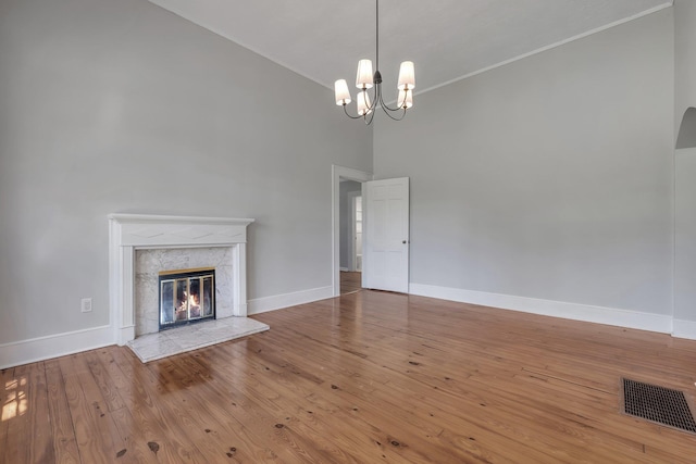 unfurnished living room featuring visible vents, baseboards, wood-type flooring, and a chandelier