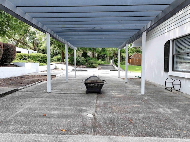 view of patio with a pergola, a fire pit, and a storage shed