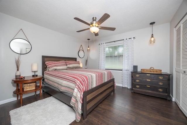 bedroom featuring a textured ceiling, ceiling fan, dark wood-type flooring, and a closet