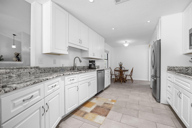 kitchen featuring light stone counters, stainless steel appliances, sink, light tile patterned floors, and white cabinetry