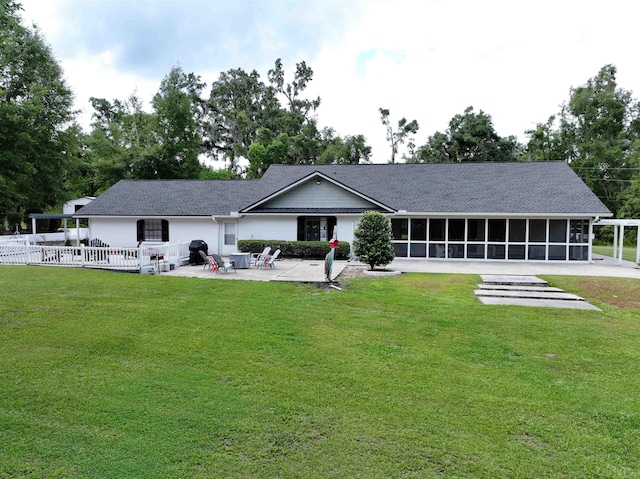 rear view of property with a sunroom, a patio area, and a lawn