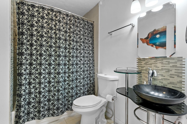 bathroom with sink, a shower with shower curtain, tasteful backsplash, tile patterned floors, and toilet