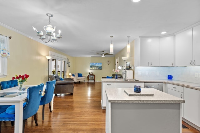 kitchen with sink, white cabinetry, hanging light fixtures, light hardwood / wood-style flooring, and stainless steel dishwasher