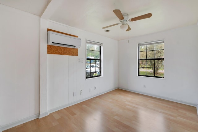 spare room featuring ceiling fan, plenty of natural light, light hardwood / wood-style floors, and a wall unit AC